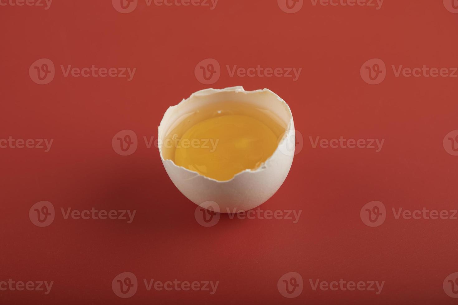 uovo organico rotto su uno sfondo rosso foto