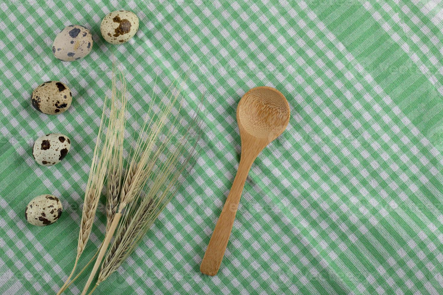 uova di quaglia e spighe di grano su una tovaglia a righe foto