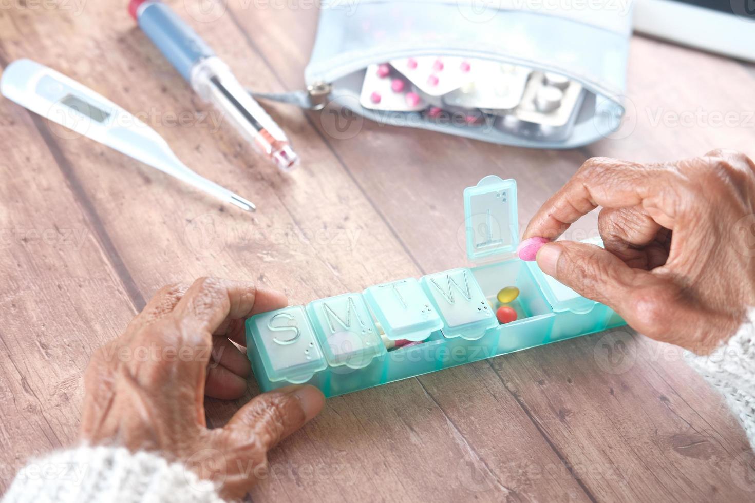 mani delle donne senior che prendono medicine da una scatola della pillola foto