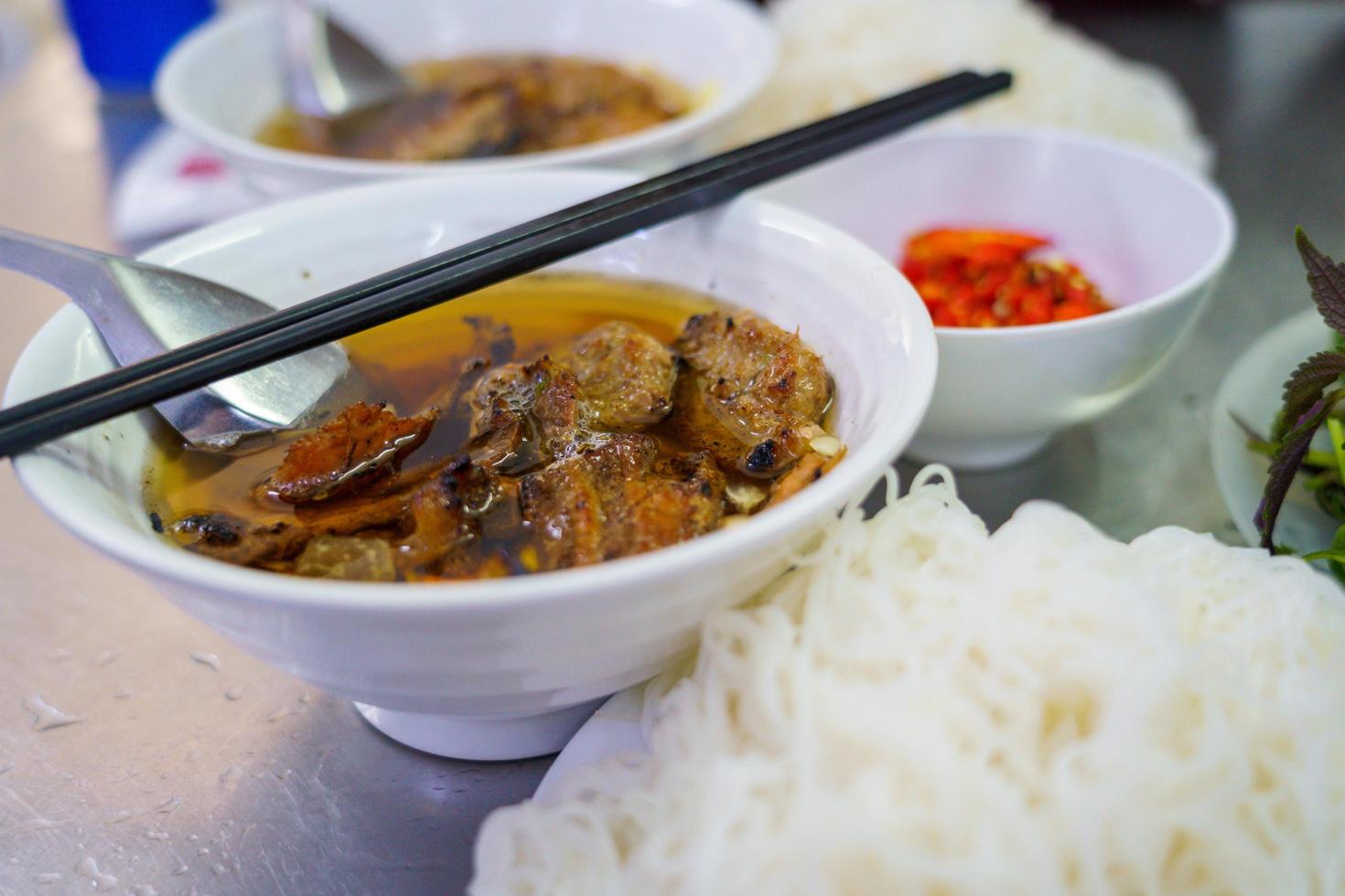 bun cha con maiale alla griglia, spaghetti di riso, verdure e zuppa nella cucina vietnamita foto