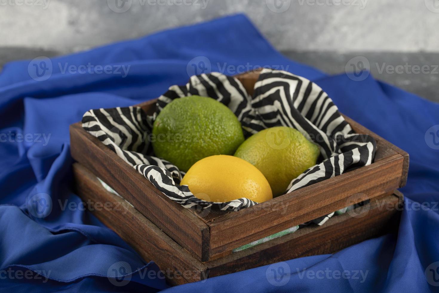 un cesto di legno con tre limoni su un panno blu foto