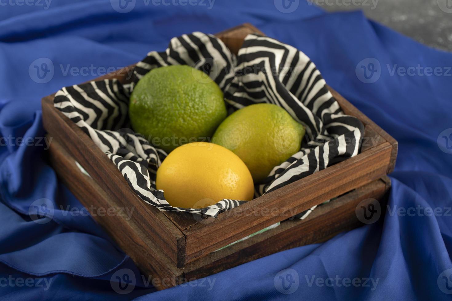 un cesto di legno con tre limoni su un panno blu foto