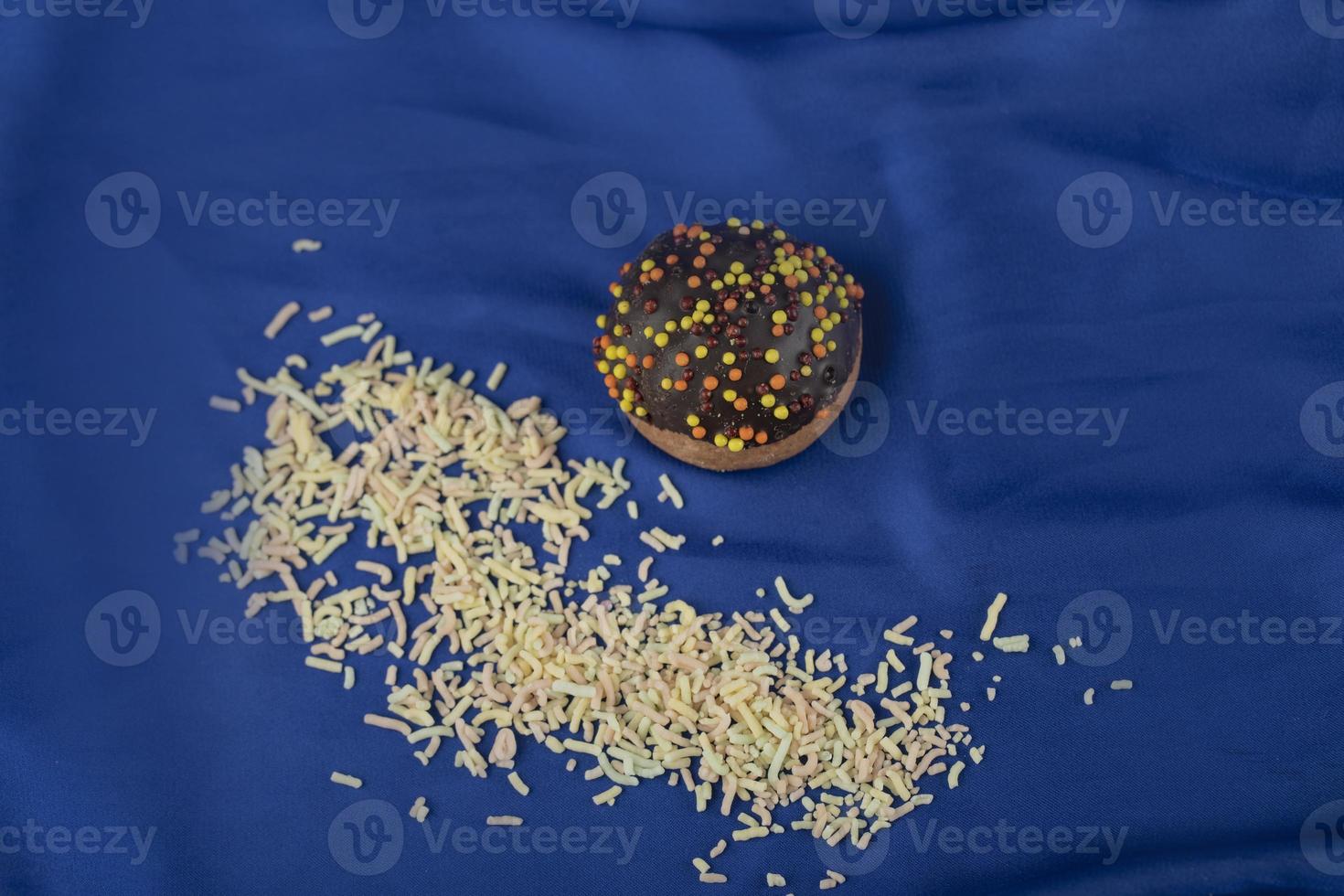 una piccola ciambella al cioccolato con codette su una tovaglia blu foto