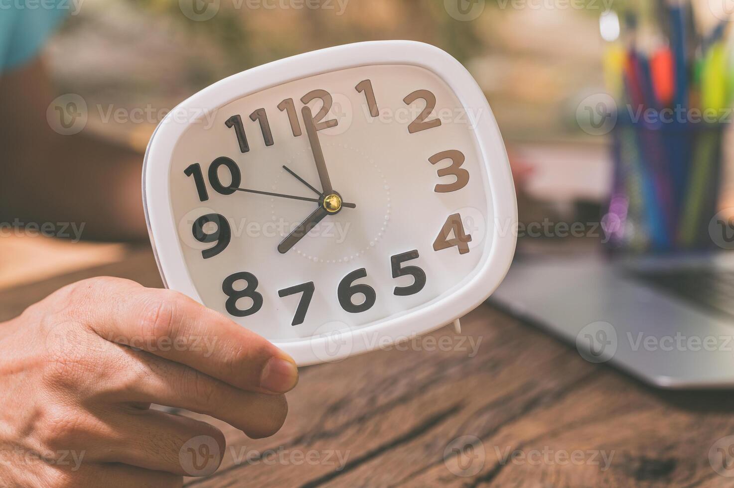 la mano di una persona che tiene un orologio alla scrivania foto