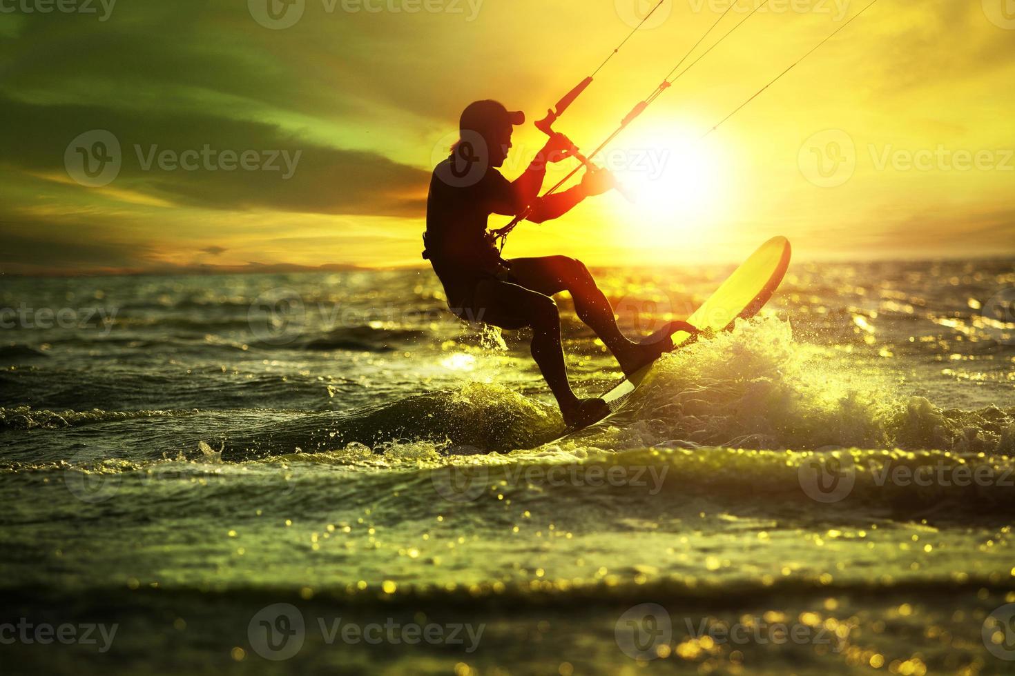 uomo giocando aquilone Surf su affrettandosi mare contro bellissimo tramonto cielo foto