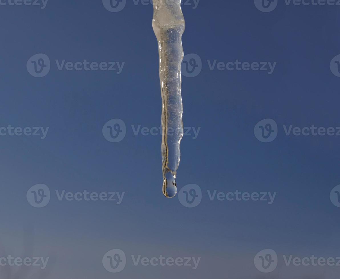 primavera gocce cascate giù a partire dal lungo cristallo fusione ghiaccioli sospeso giù prima chiaro blu cielo su luminosa soleggiato scongelare giorno. il concetto di il inizio di molla, il fine di inverno, scongelare. foto