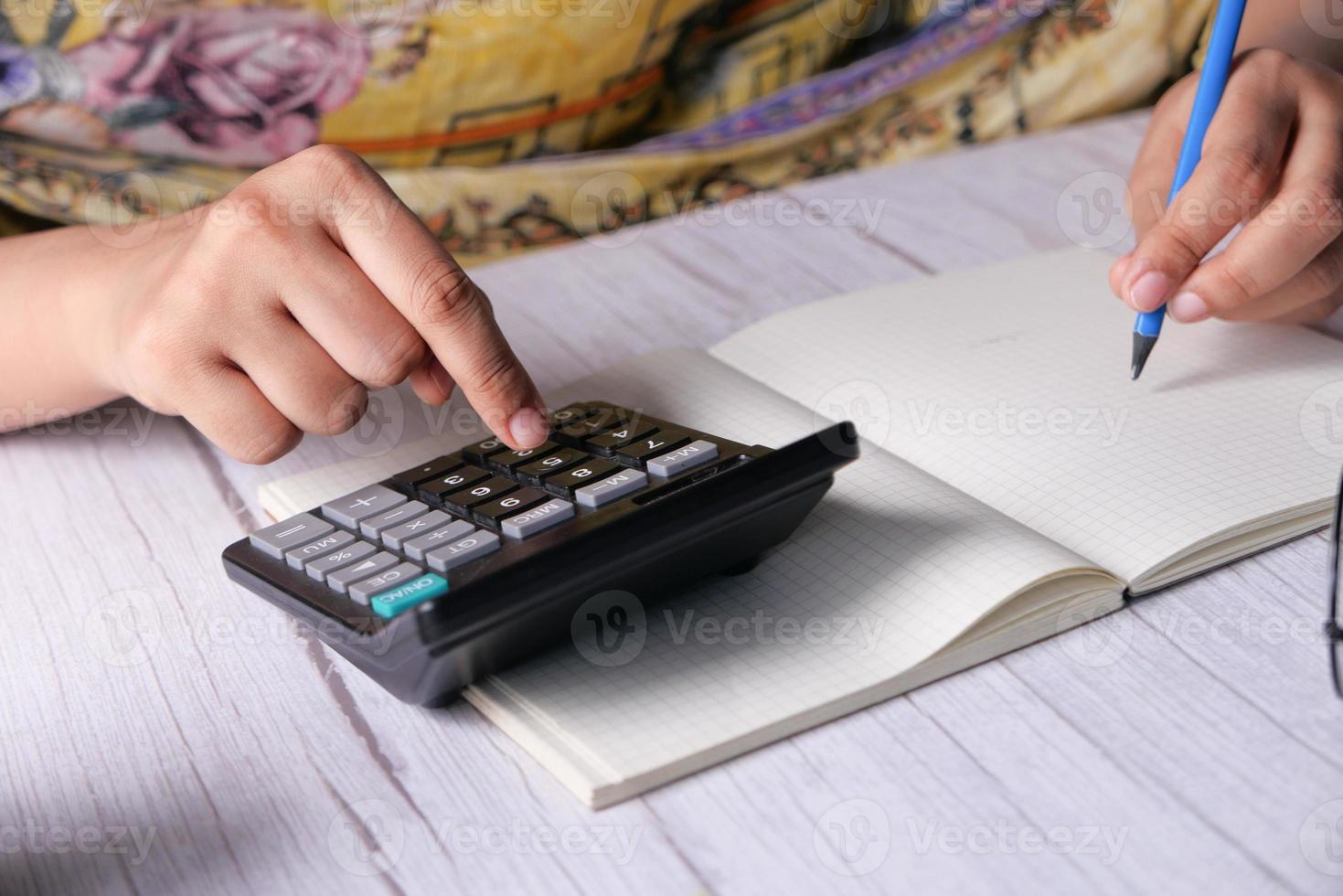 mano della donna utilizzando la calcolatrice sulla scrivania in ufficio foto