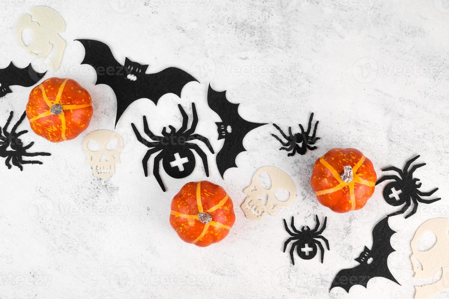 diagonale Halloween piatto posare sfondo con spaventoso decorazioni. zucche, teschi, pipistrelli e ragni su calcestruzzo tavolo. superiore Visualizza. foto