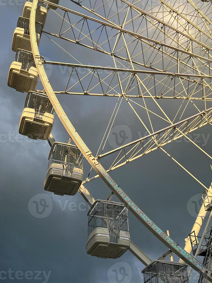 Ferris ruota nel il divertimento parco su sfondo di grigio nuvoloso cielo con nuvole. Basso angolo Visualizza di un' grande Ferris ruota. foto