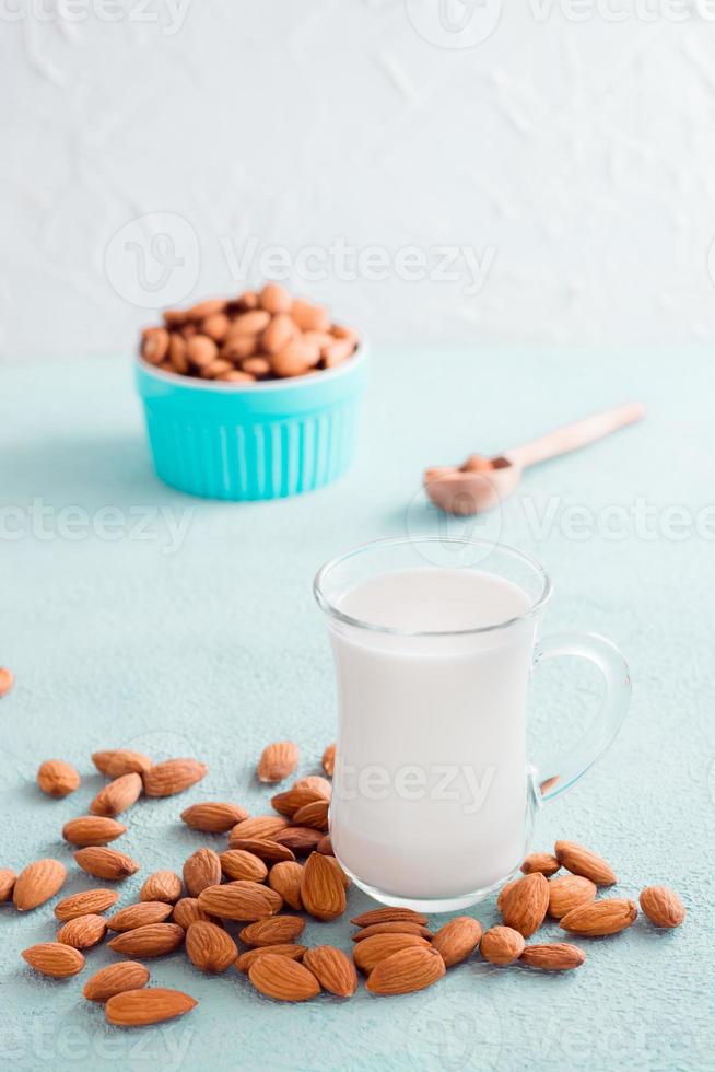 fresco mandorla latte nel un' bicchiere e noccioline Il prossimo per esso su un' leggero tavolo. alternativa nutrizione, fonte di vitamine. verticale Visualizza foto