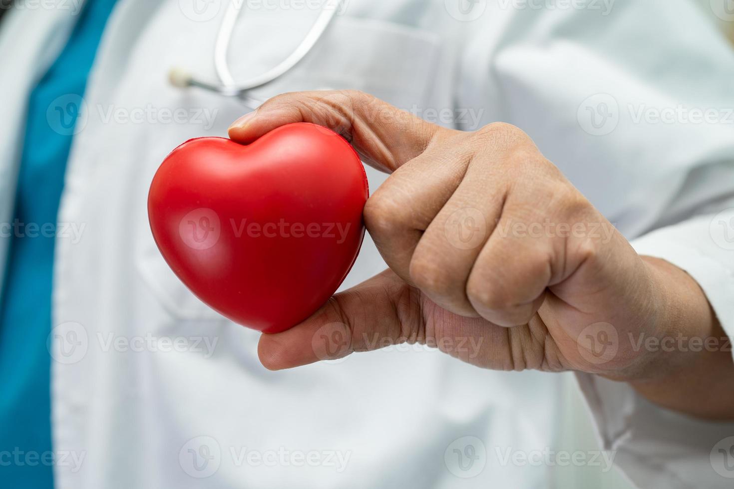 medico che tiene un cuore rosso nel reparto ospedaliero, concetto medico sano e forte. foto