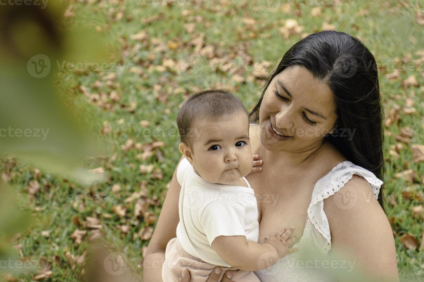 bella madre con sua poco figlia seduta nel il parco. foto