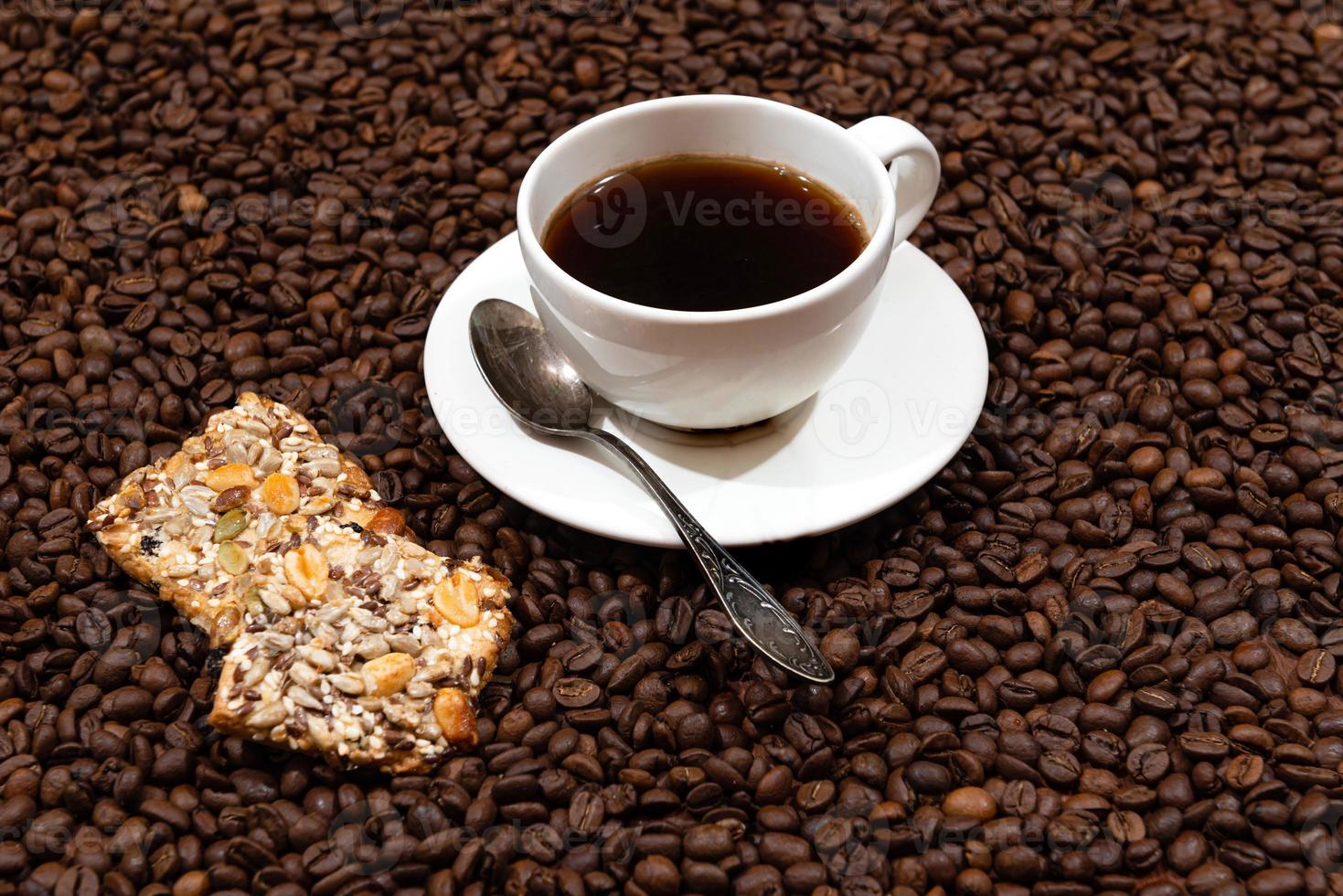 tazza di caffè bianco e biscotti sullo sfondo di chicchi di caffè foto