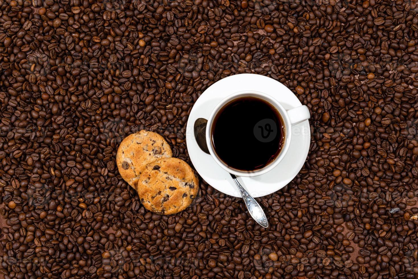 tazza di caffè bianco e biscotti sullo sfondo di chicchi di caffè foto