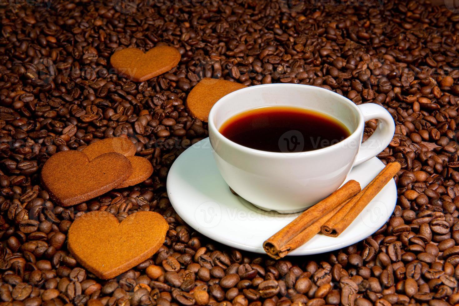 tazza di caffè bianco, bastoncini di cannella e biscotti di pan di zenzero a forma di cuore foto