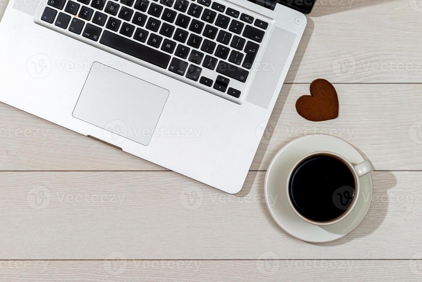area di lavoro con laptop, tazza da caffè e cuore di pan di zenzero foto