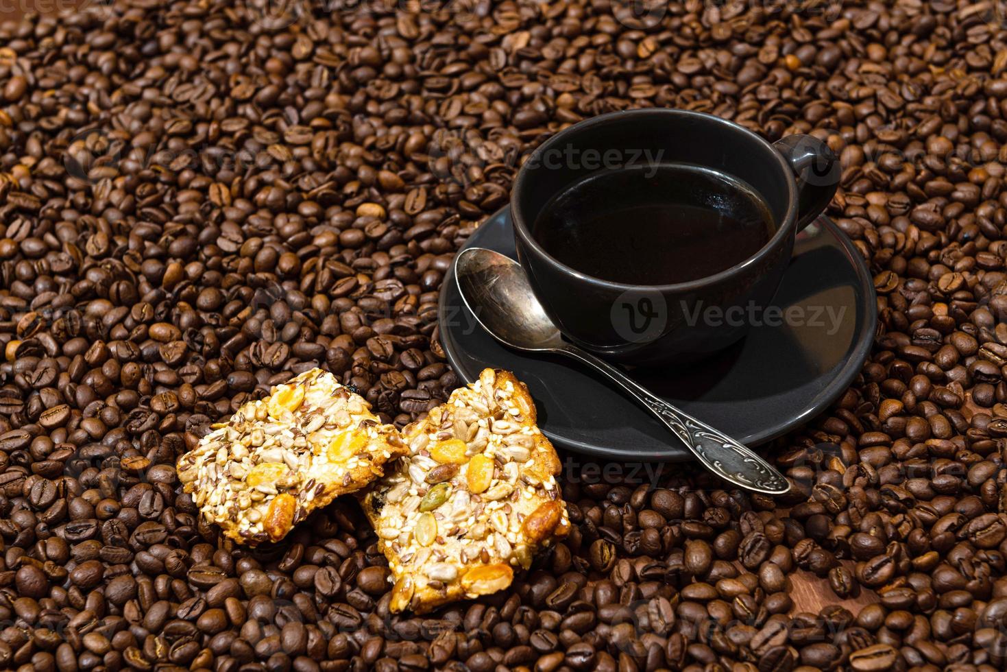 tazza di caffè nero e biscotti sullo sfondo di chicchi di caffè foto