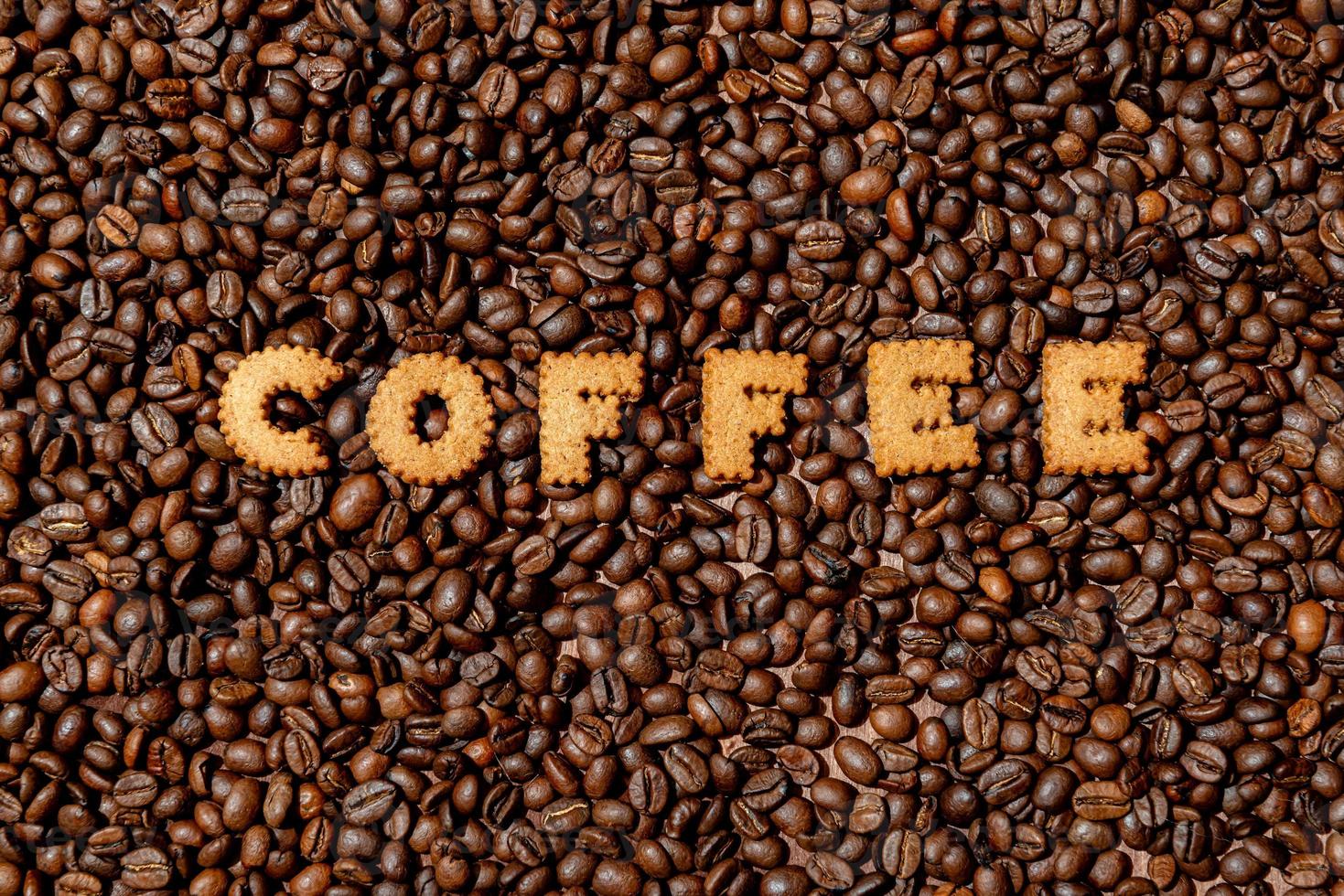 la parola caffè composta da lettere biscotto su uno sfondo scuro del chicco di caffè foto