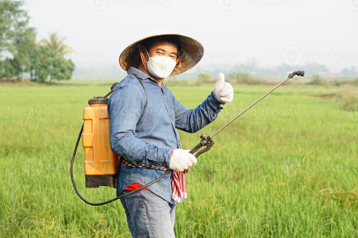 asiatico contadino è spruzzatura biologico fertilizzante a risaia campo. pollice su. concetto utilizzando amichevole Prodotto con ambiente agricoltura con no sostanze chimiche usando. sicurezza con utente e ambiente. foto