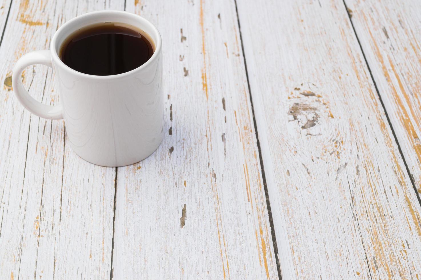 una tazza di caffè su una scrivania in legno foto