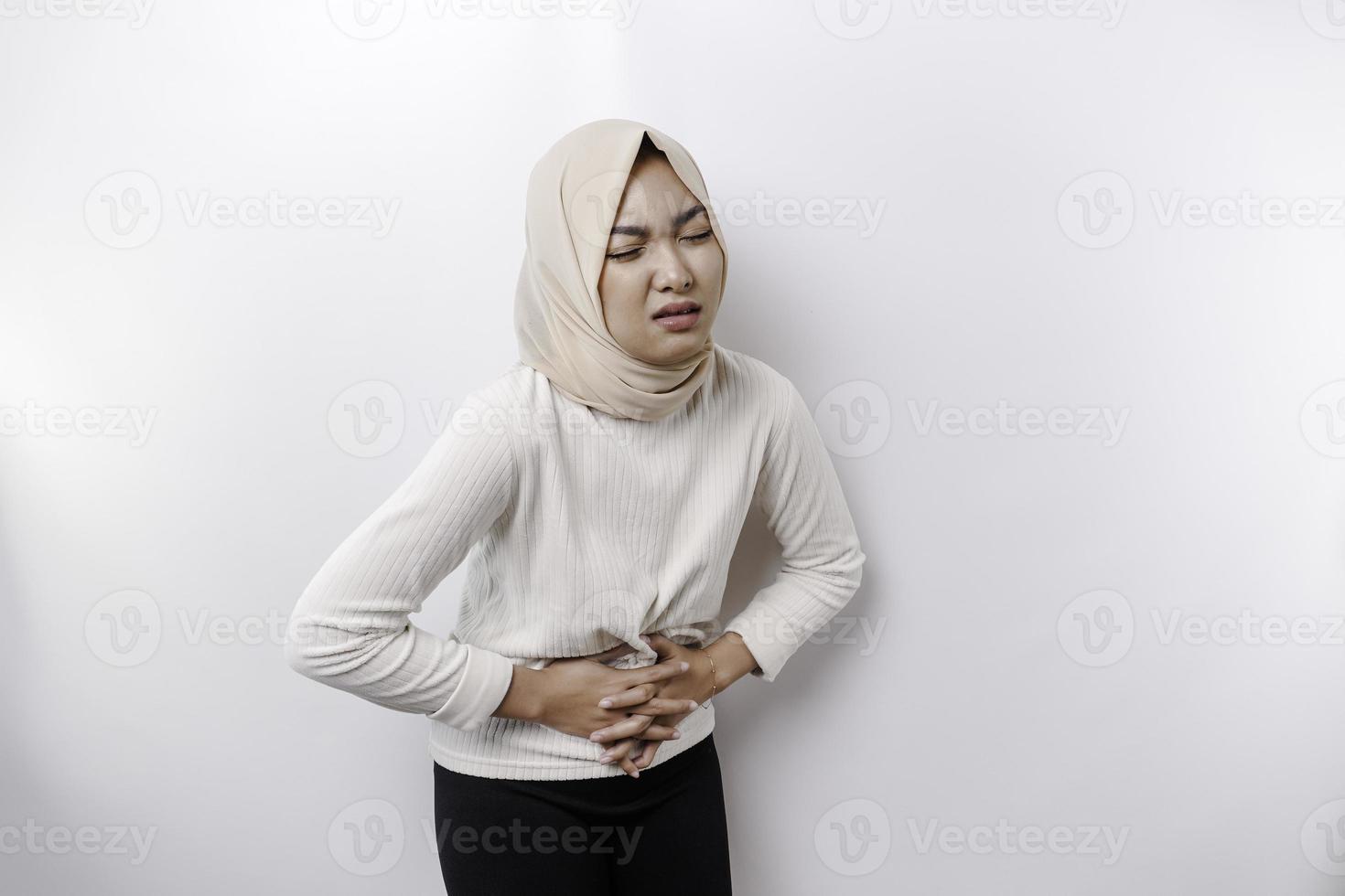 un asiatico musulmano donna è digiuno e Affamato e toccante sua pancia mentre guardare a parte pensiero di che cosa per mangiare foto
