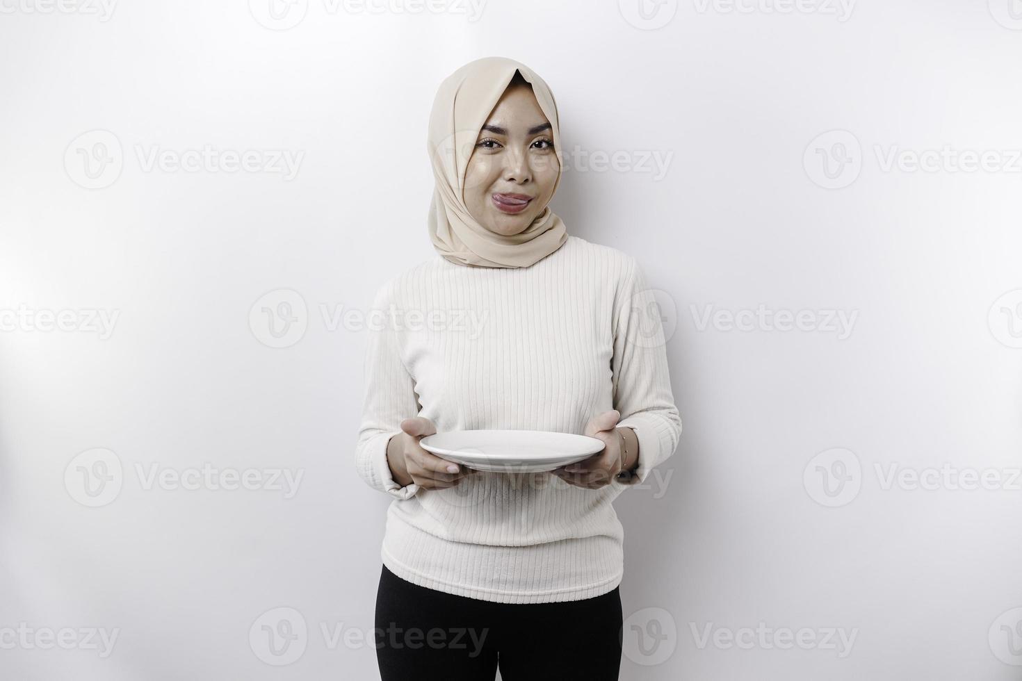 un asiatico musulmano donna è digiuno e Affamato e Tenere un' piatto mentre guardare a parte pensiero di che cosa per mangiare foto