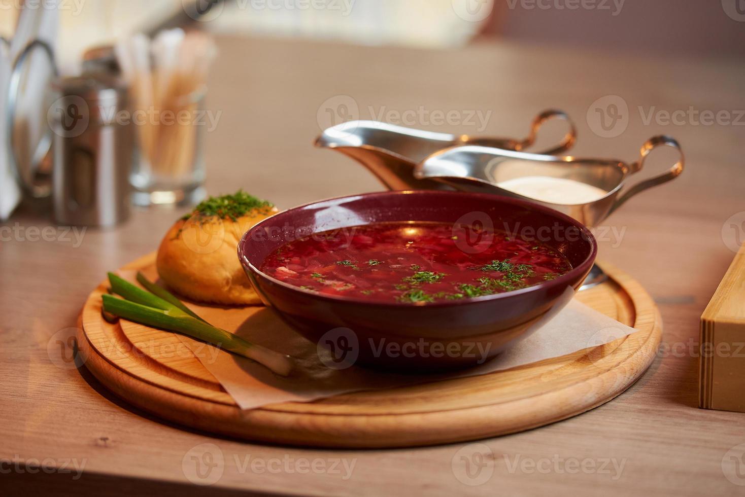 un borsch ucraino con pampushka, cipolla e panna acida su un vassoio di legno foto