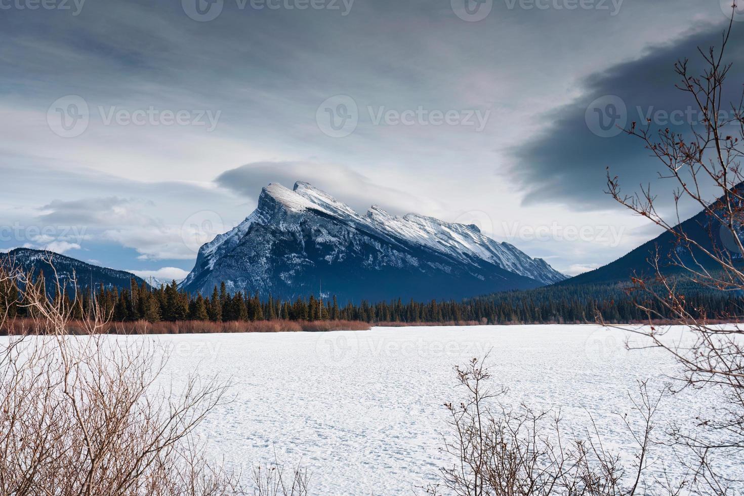 congelato vermiglio lago con montare rundle e neve coperto nel inverno su soleggiato giorno a Banff nazionale parco foto