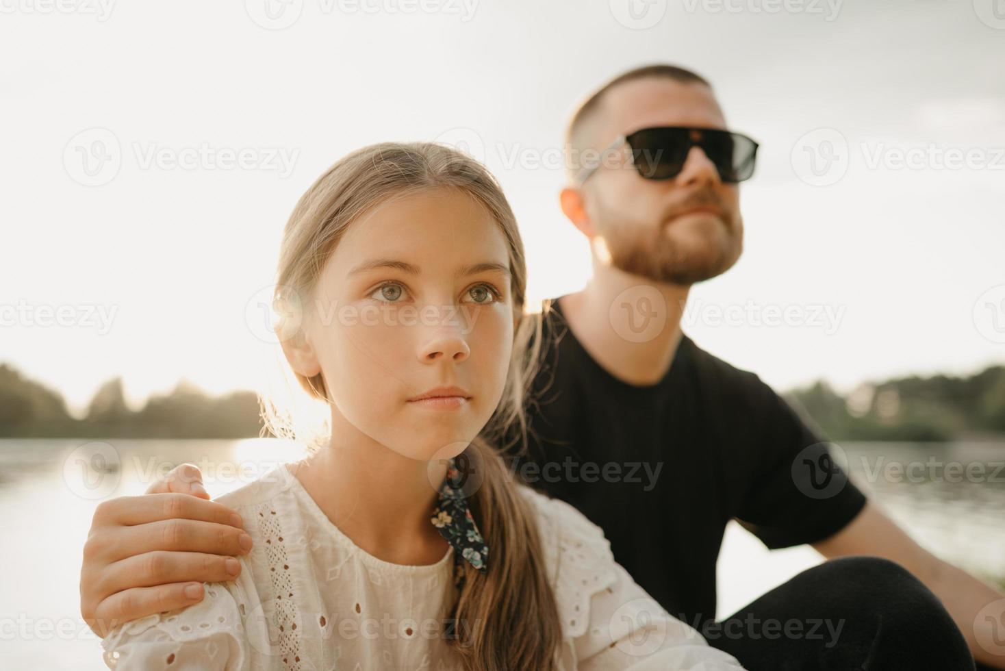 un ritratto ravvicinato di una giovane ragazza che posa con suo padre con la barba che la abbraccia foto