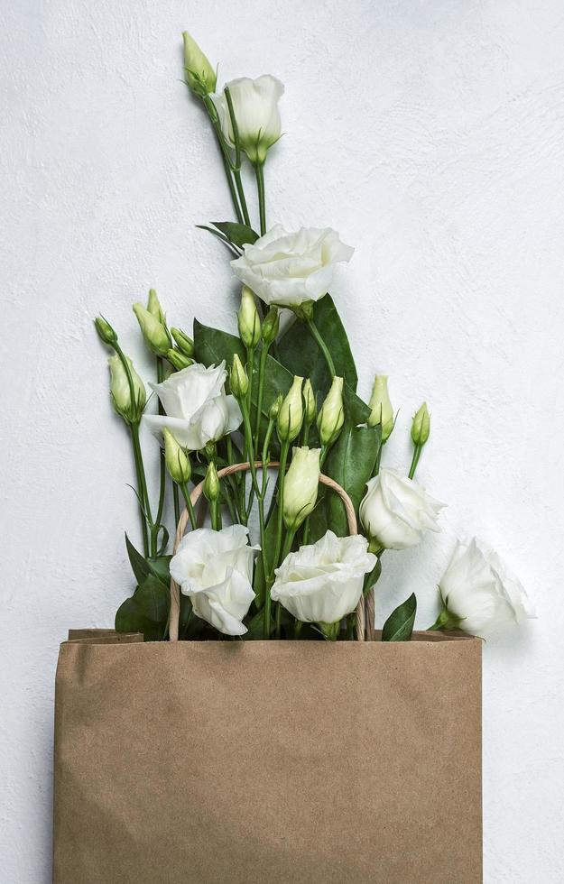 bouquet di eustoma in un sacchetto di carta marrone su sfondo bianco, delicata rosa giapponese foto