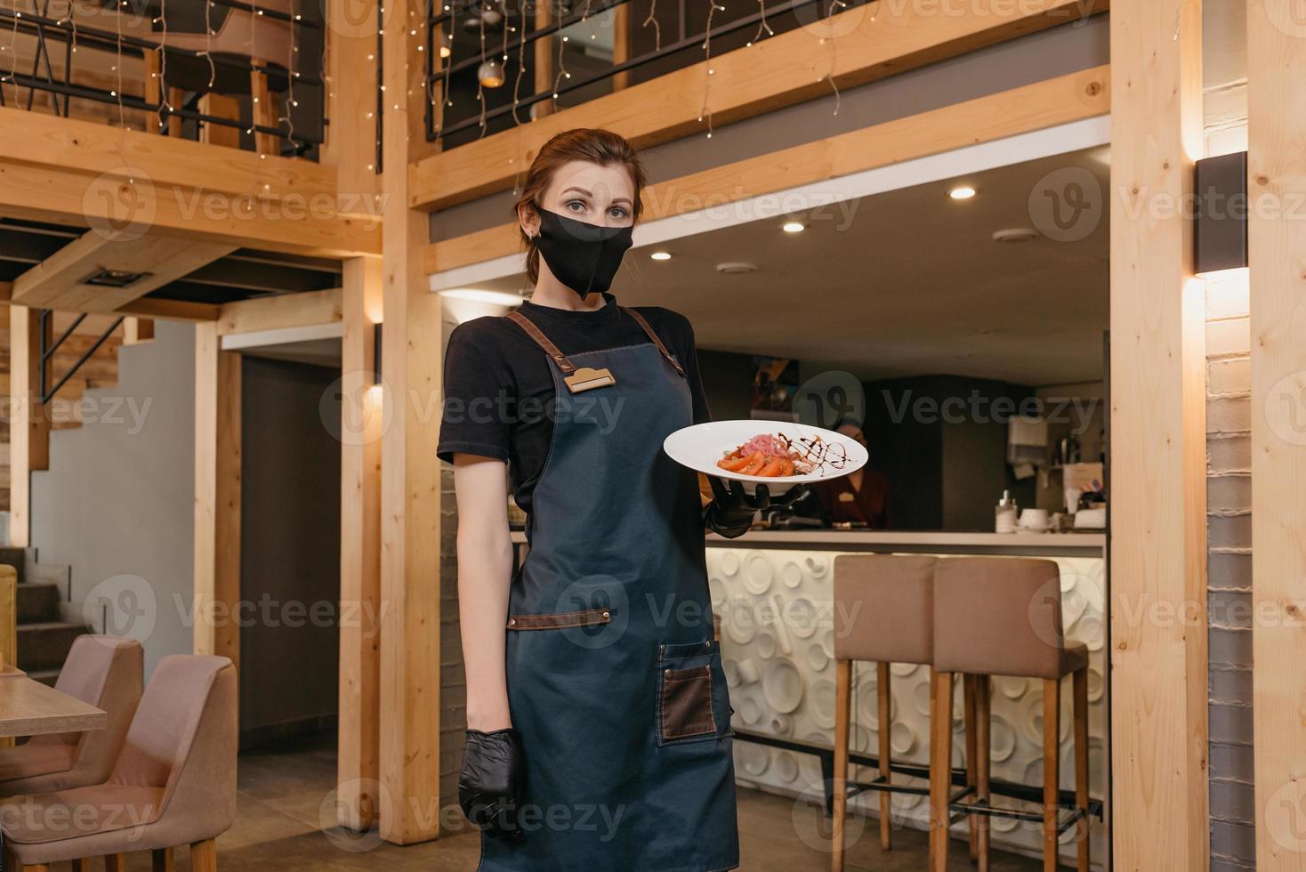 una cameriera che indossa una maschera nera tiene in mano un'insalata di menta e dolendwitz foto