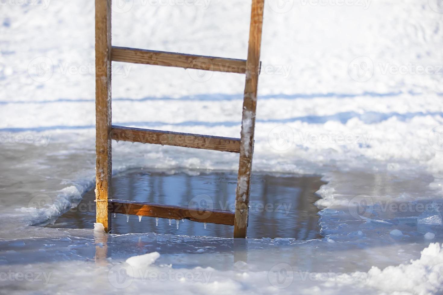 un buco nel ghiaccio nel un' inverno lago con un' di legno scala a pioli. festa di il battesimo di Gesù. foto