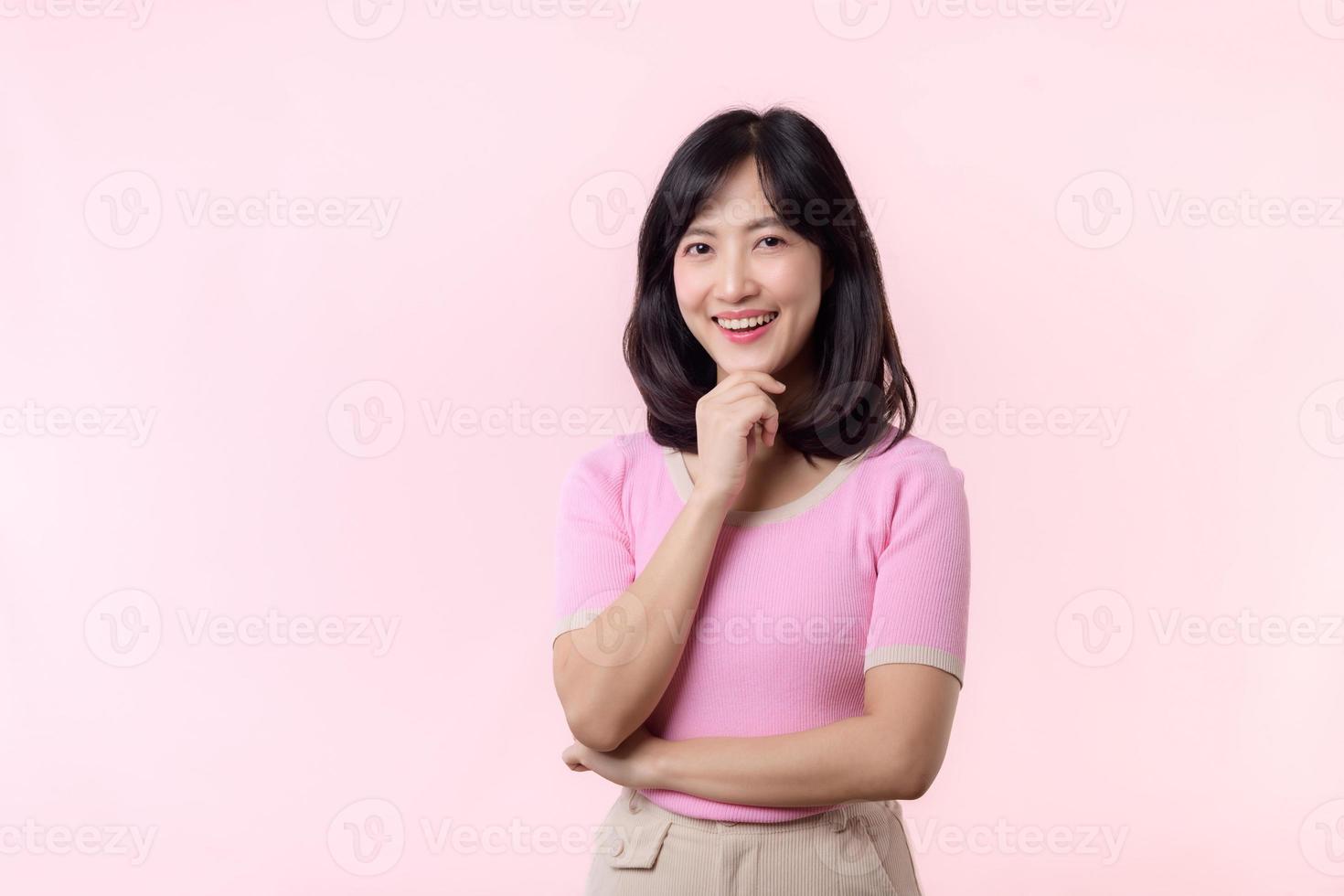 ritratto bellissimo giovane asiatico donna riflessivo pensiero un idea isolato su rosa pastello sfondo. adolescenziale femmina persona bella Sorridi con pensiero gesto concetto. foto