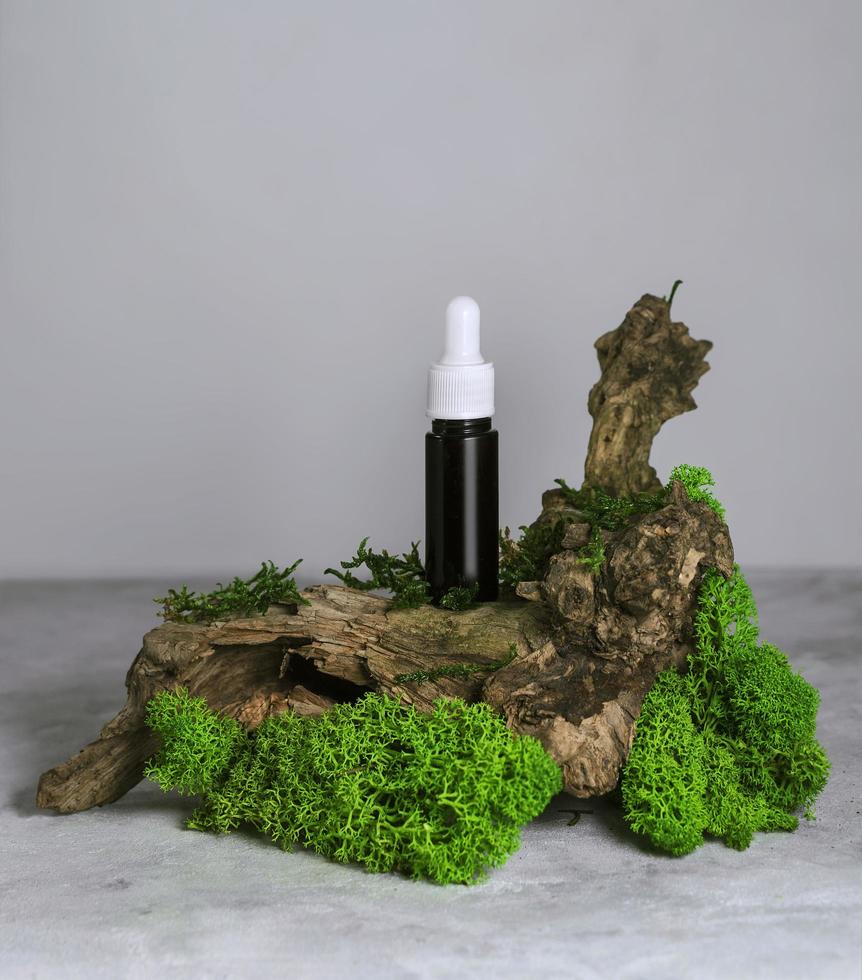 bottiglia di vetro di siero con una pipetta sul muschio verde, concetto cosmetico termale biologico naturale foto
