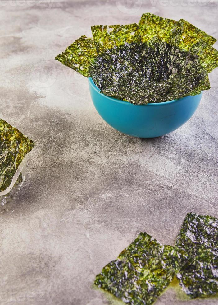 alghe nori croccanti in una ciotola blu su sfondo grigio foto
