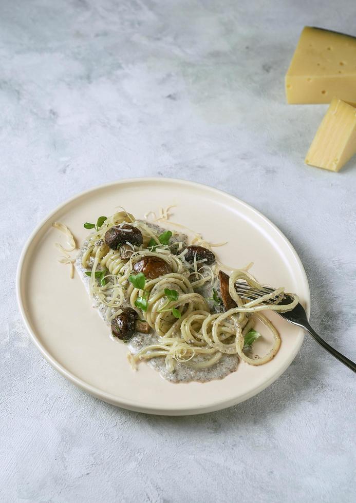 un piatto di pasta con formaggio e salsa di funghi su uno sfondo di marmo grigio foto