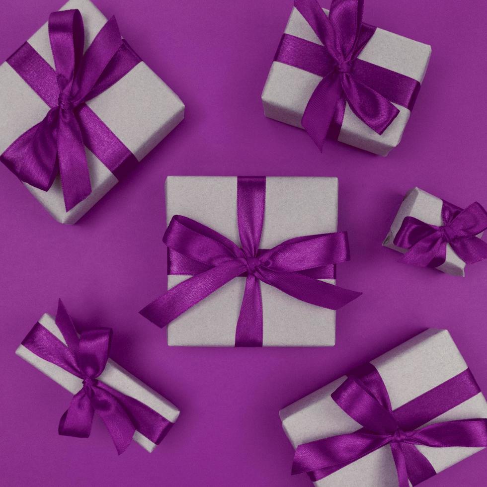 scatole regalo avvolte in carta artigianale con nastri viola e fiocchi, laici piatta monocromatica festiva foto