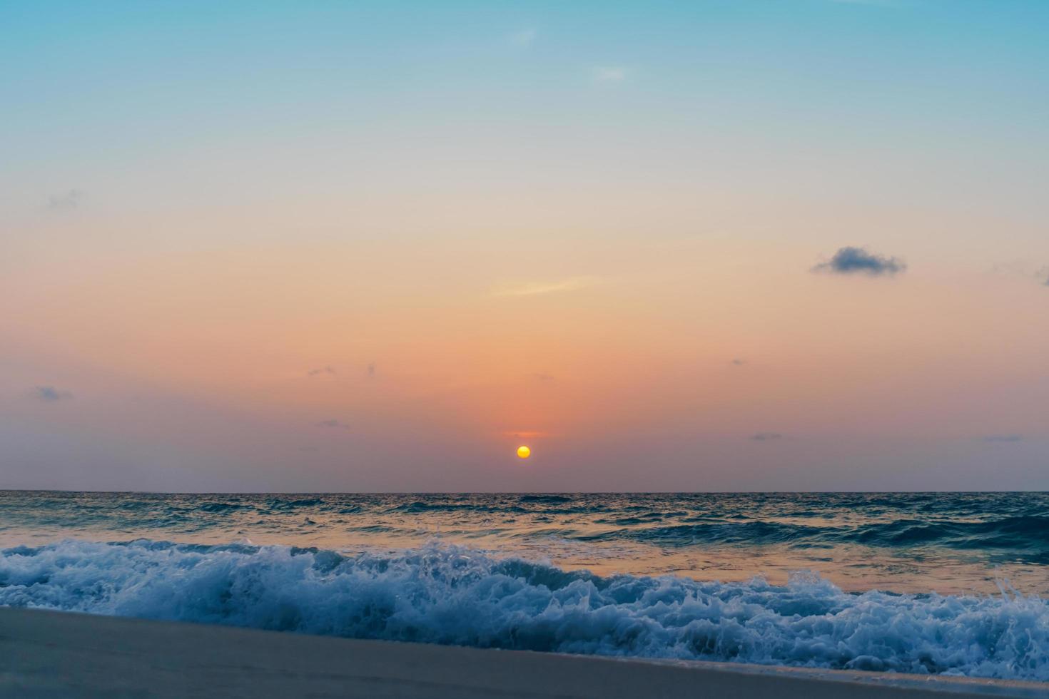 onde del mare oceano colorato durante l'alba o il tramonto con il sole sullo sfondo foto