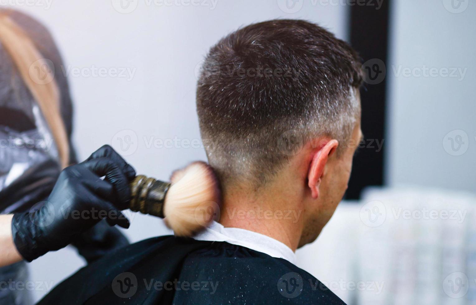 un' parrucchiere con sicurezza le misure per covid19, detiene forbici nel il suo mani e tagli un' uomo, sociale distanza, taglio capelli con gomma da cancellare guanti foto