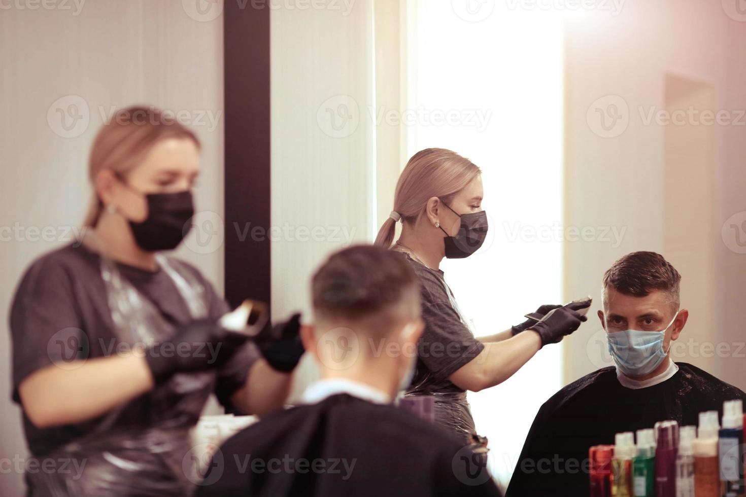 parrucchiere con sicurezza le misure per covid19, tagli un' uomo nel un' medicina maschera, sociale distanza, taglio capelli con un' medico maschera e gomma da cancellare guanti. foto