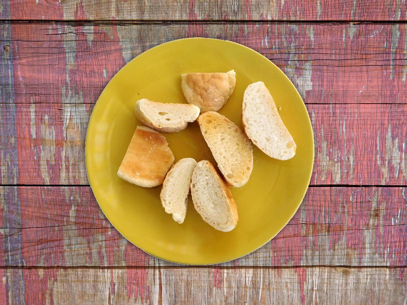pane a fette su un piatto giallo sul fondo della tavola in legno foto