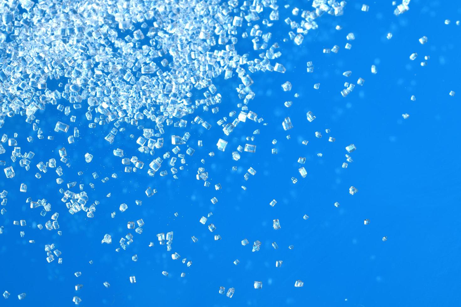 superiore Visualizza di bianca cristallo zucchero isolato su blu sfondo foto