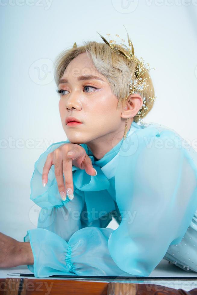 un' donna con bionda capelli e un' blu vestito in posa con arricciato braccia e un' arrossendo viso foto