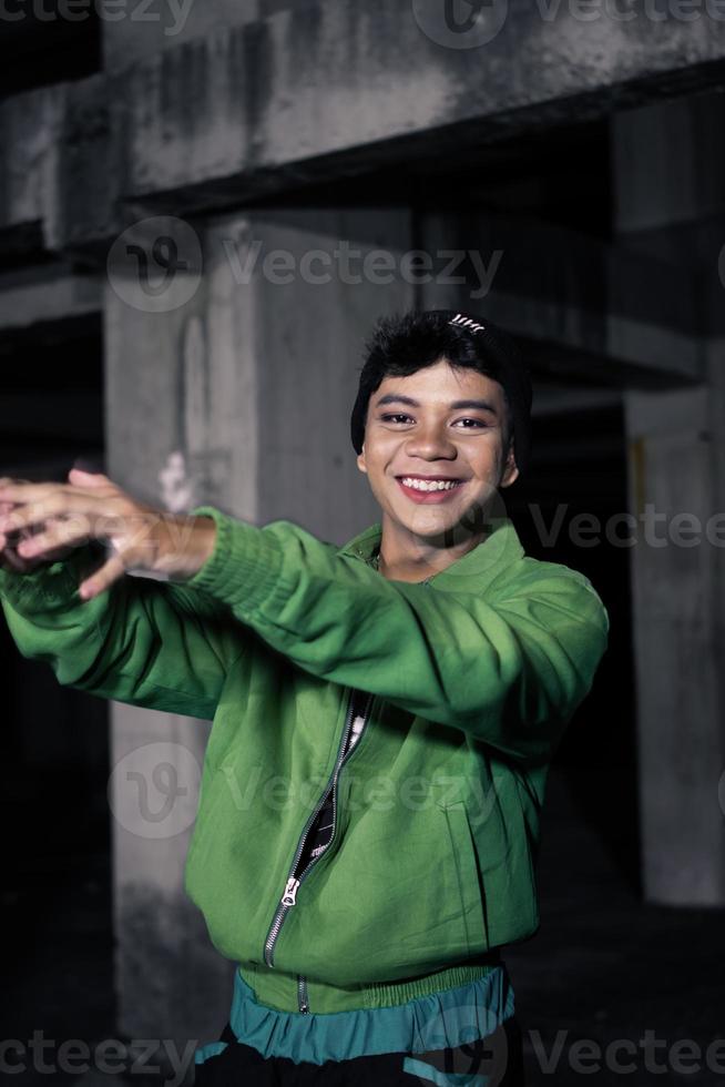 un asiatico uomo sorrisi mentre indossare un' verde paracadute giacca e nero pantaloni foto