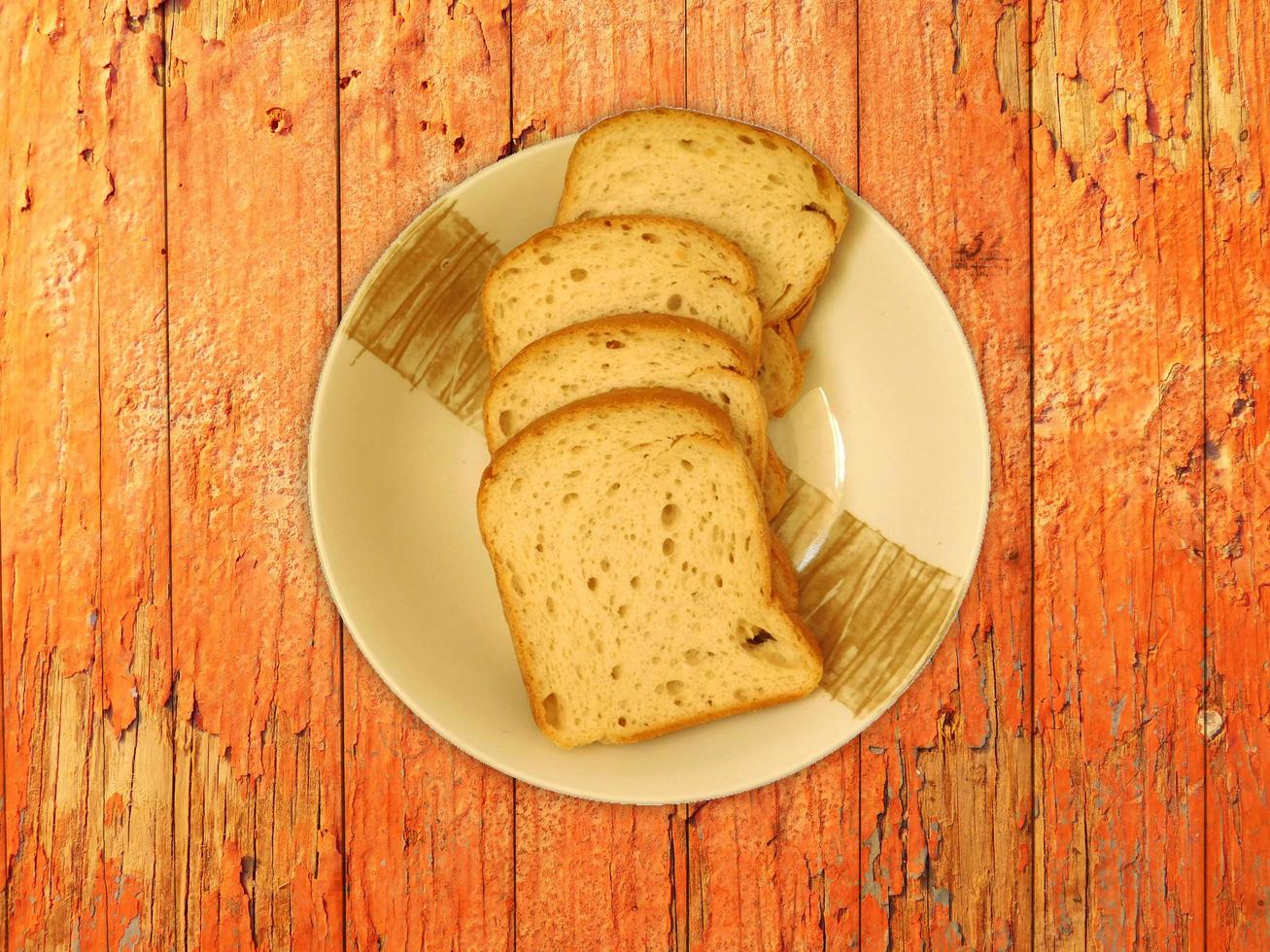 pane a fette su un piatto di ceramica su uno sfondo di tavolo in legno foto