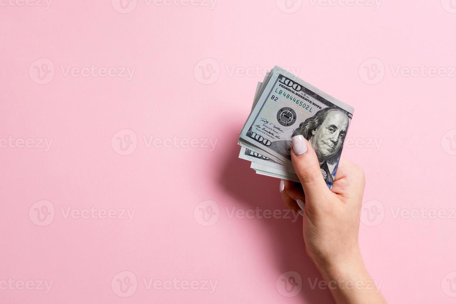 un' imballare di uno centinaio dollaro fatture nel femmina mano su colorato sfondo. stipendio concetto con copia spazio foto
