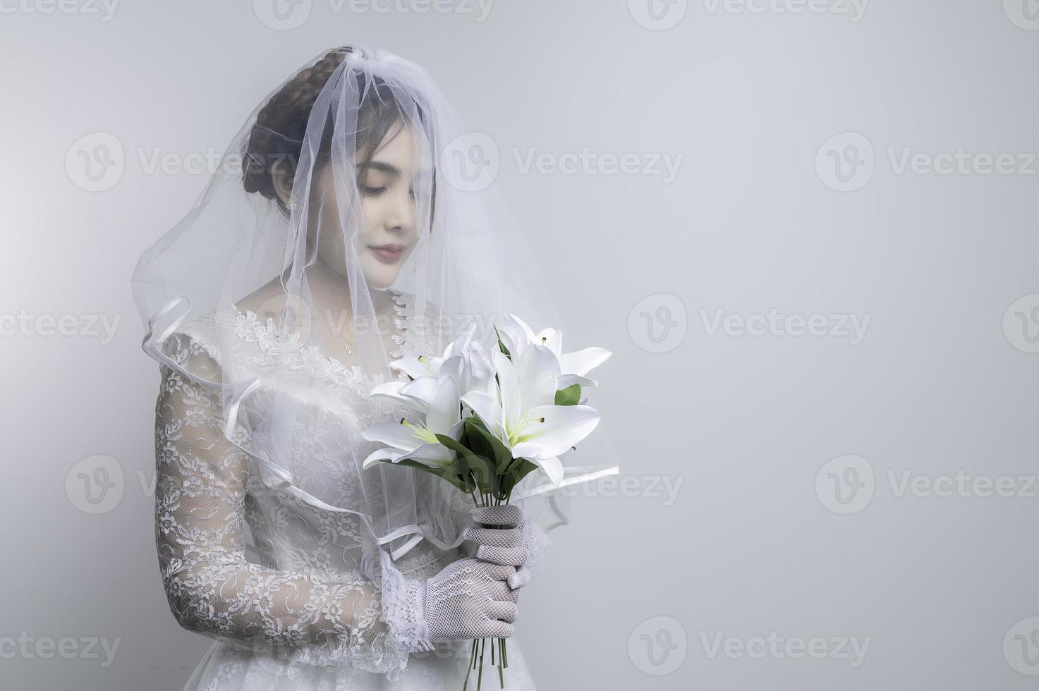 ritratto di asiatico donna indossare sposa con fiore su bianca sfondo, matrimonio concetto foto