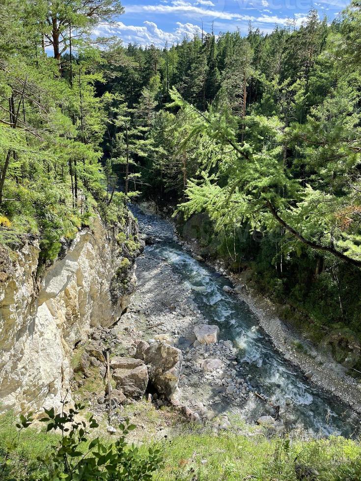 montagna fiume fluente nel un' valle fra un' foresta e un' alto scogliera, buriazia, Russia foto