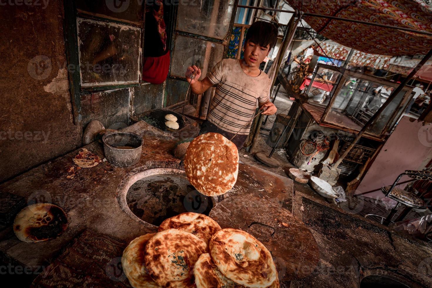 un vecchio venditore vendita al forno naan su il vecchio strada di kashgar foto