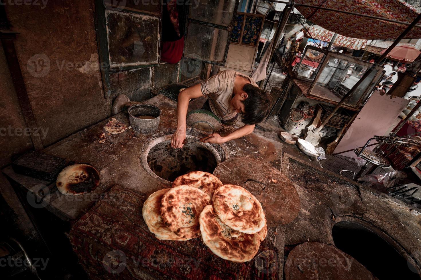 un vecchio venditore vendita al forno naan su il vecchio strada di kashgar foto